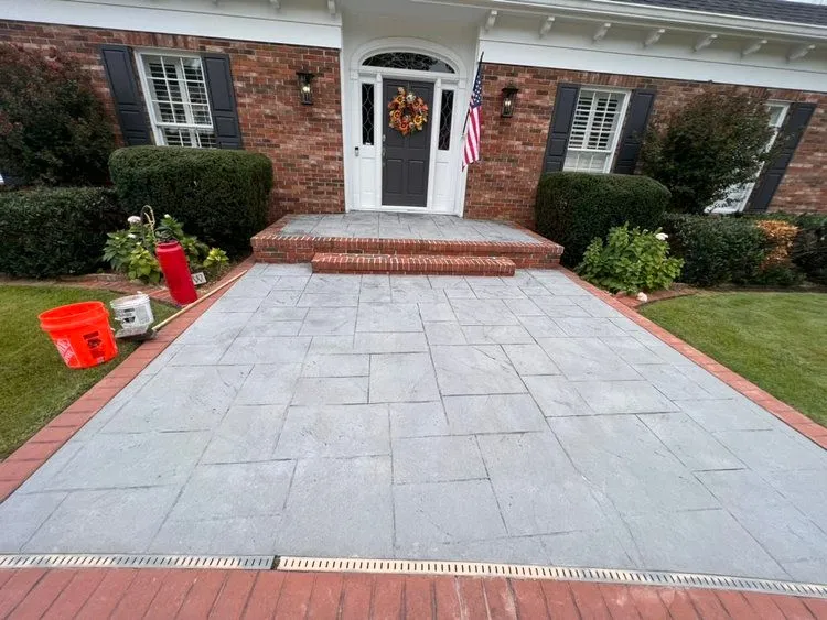 gray stone stamped concrete driveway with brick border